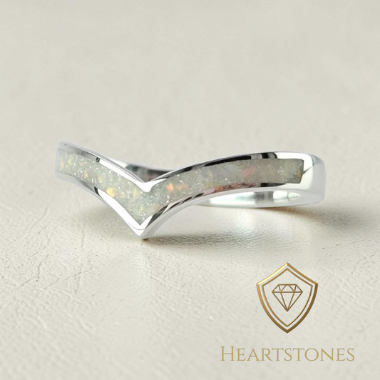 Silver ring with opal inlay on a beige background, featuring the Heartstones brand logo.